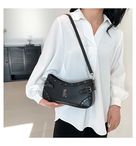 Detail of black punk shoulder bag featuring metallic studs and skull emblem accents