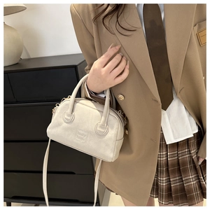 Detail view of cream white PU leather handbag with lady bags lettering and dual handles