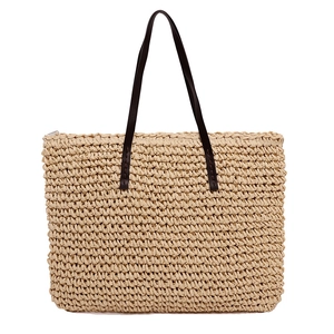 Minimalist woven straw tote bag with brown leather handles on white background