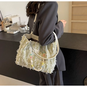Detail der hellgrünen Tweed-Tasche mit Fransen, Lederriemen und Perlenketten-Verzierung