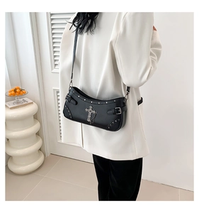 Detail view of black punk style shoulder bag featuring large silver cross and chain accents