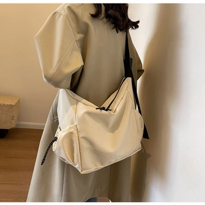 Detail of cream canvas crossbody bag showing large capacity and adjustable wide black strap