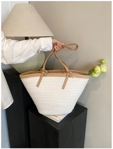 Texture détaillée d'un sac bandoulière beige tissé main avec anses en cuir marron et nœuds