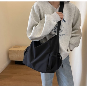 Detail view of large black nylon tote bag with drawstring side and adjustable strap