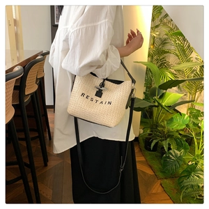 Détail du sac seau tissé beige avec broderie noire RESTAIN et fermoir métallique élégant