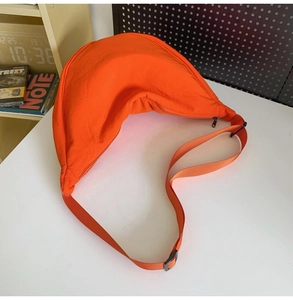 Top-down view of a bright orange nylon crescent crossbody bag with adjustable strap