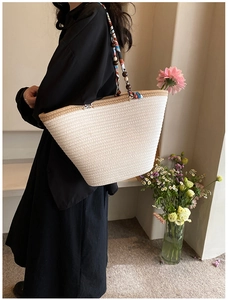 Détail du sac tissé crème avec foulard floral bohème enroulé autour de la poignée