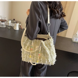 Detailansicht der minzgrünen Tweed-Tasche mit Fransen und bunter Acryl-Perlenkette