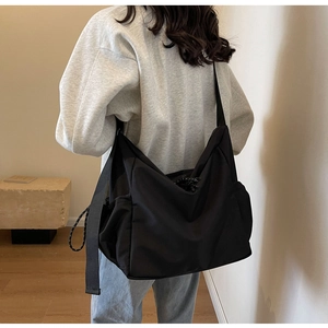Macro detail of a large black nylon crossbody bag with zipper and drawstring elements