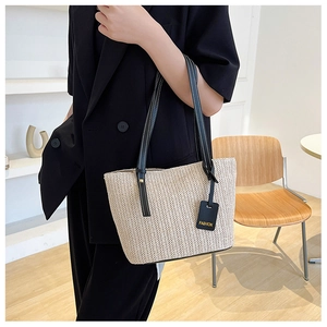 Close-up of beige woven tote bag with black straps and white stitching on a model