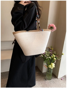 Détail du sac cabas tissé avec bandoulière géométrique et perles décoratives en bois