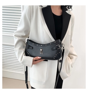 Detail of black leather half-moon shoulder bag with silver skull and stud embellishments