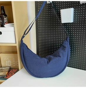 Detail of a dark blue crescent crossbody bag made of durable nylon with adjustable strap