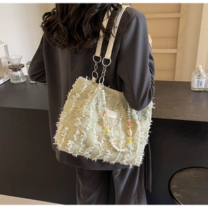 Detailansicht der hellgrünen Tweed-Schultertasche mit Fransen und Perlenketten-Accessoire