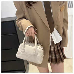 Detail of beige Boston handbag featuring textured leather and embossed lady bags logo