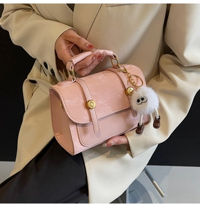 Pink PU leather handbag detail with suede flap, gold hardware, and a cute plush monster charm