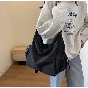 Close-up of large black canvas crossbody bag with side drawstring details for women