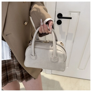 Detail view of small Boston style PU leather handbag with pebble texture and gold zippers