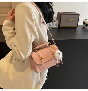 Detail of pink PU leather handbag with white fluffy monster charm on a stylish crossbody bag