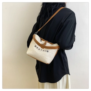 Détail de la texture tissée et de la bandoulière en cuir marron du sac blanc