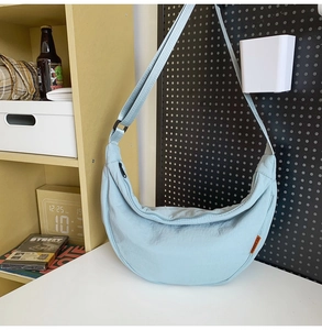 Detailed close-up of light blue nylon crescent crossbody bag with adjustable wide strap