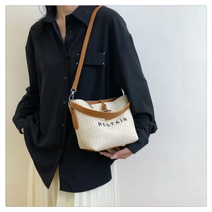 Détail du sac bandoulière tissé avec lanière en cuir marron et lettrage noir chic