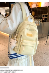Detailed view of cream-colored textured backpack with cute white plush bear pendant accessory