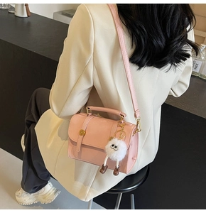 Fashionable light pink PU leather crossbody bag with a white plush charm worn by a model