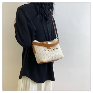 Detail of woven crossbody bag with leather trim and RESTAIN embroidery on shoulder