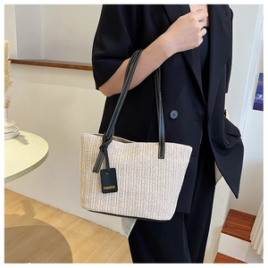 Detail of woven straw tote bag with black leather straps and white contrast stitching