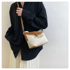 Close-up of woven straw crossbody bag with brown leather trim and metal hardware details