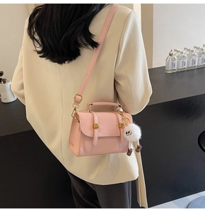 Detailed close-up of a pink PU leather crossbody bag with a white plush monster charm