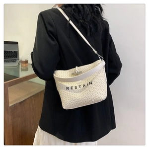 Détail du sac seau tissé beige avec lanières en cuir blanc et broderie RESTAIN