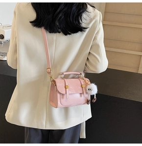 Detailed view of pink PU leather square bag with white plush ball charm and gold buckle