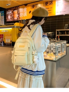Close-up of stylish beige PU leather backpack with a cute white cloud pendant detail