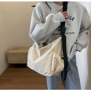 Detail view of large beige canvas crossbody bag with practical side drawstring pocket