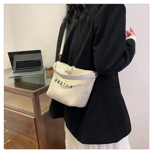 Detail of woven crossbody bag with white leather handle and RESTAIN black embroidery