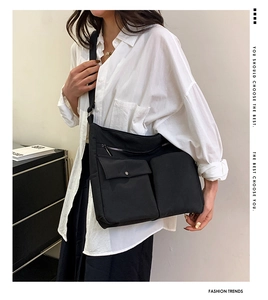 Dettaglio di una borsa a tracolla nera in nylon con tasche grandi e tracolla regolabile