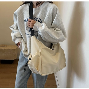 Macro detail of beige canvas crossbody bag with adjustable wide black shoulder strap