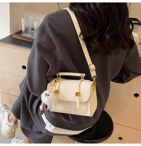 Detail of cream white PU leather crossbody bag with cute plush monster charm and gold studs