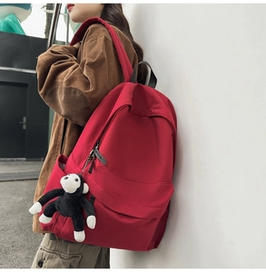 Detail of red nylon backpack with hidden zipper pocket and plush monkey keychain accessory