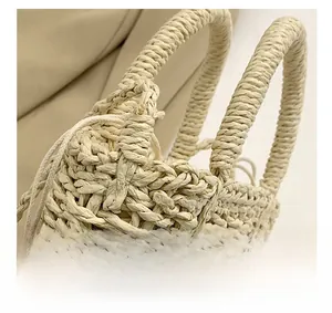 Detail of straw woven handbag with cylindrical handles and pink crochet flower charm