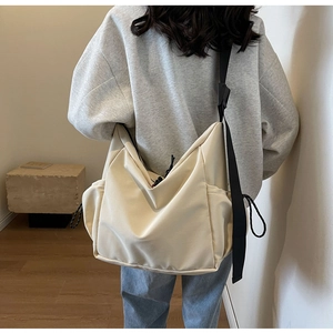 Detail view of cream white tote bag featuring adjustable black strap and side pocket