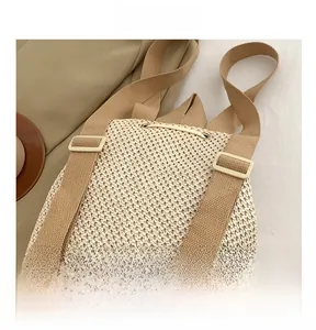 Detail view of the beige straw backpack showing adjustable straps and drawstring closure