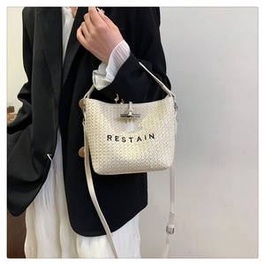 Détail du sac seau tissé avec broderie RESTAIN et poignée en cuir de qualité