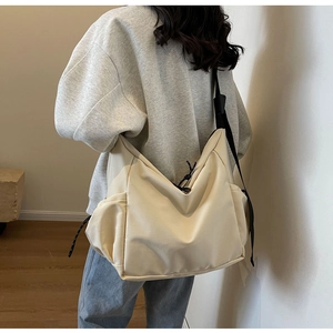 Detail view of cream canvas hobo bag with black wide strap and side drawstring pockets