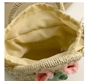 Macro shot of straw handbag featuring floral crochet detail and yellow drawstring liner