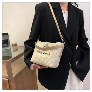 Détail du sac seau tissé beige avec broderie RESTAIN et bandoulière en cuir PU kaki