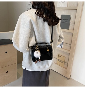 Detail of black velvet handbag with golden hardware and white monster charm on a model