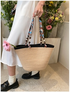 Détail d'un sac cabas en paille tressée avec anse en foulard de soie et perles en bois